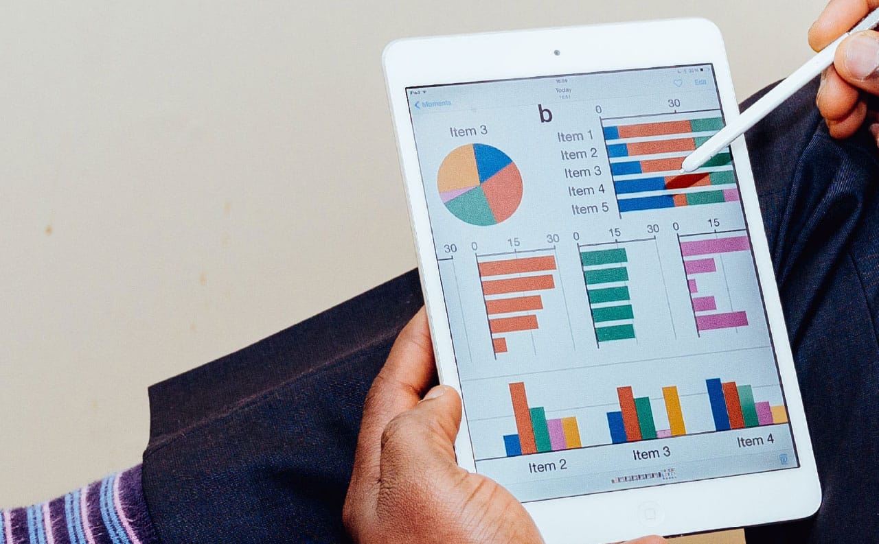 Foto in primo piano di un tablet con visualizzati sullo schermo grafici di andamenti economici, per rappresentare la gestione amministrativa del CRM per centri audioprotesici